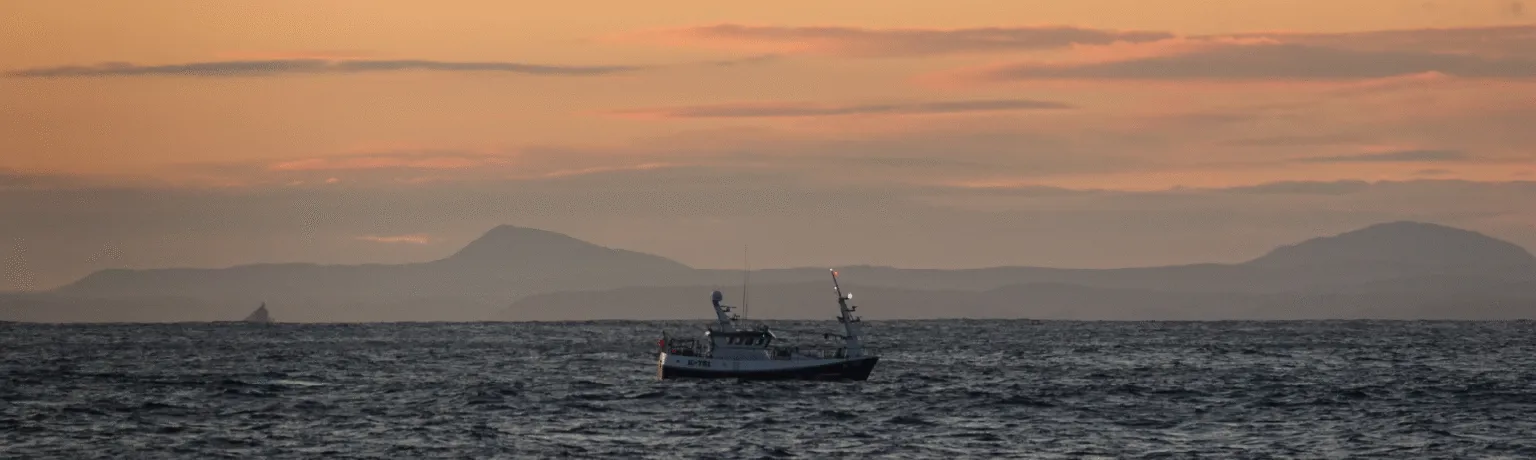 A boat on the sea at sunset.